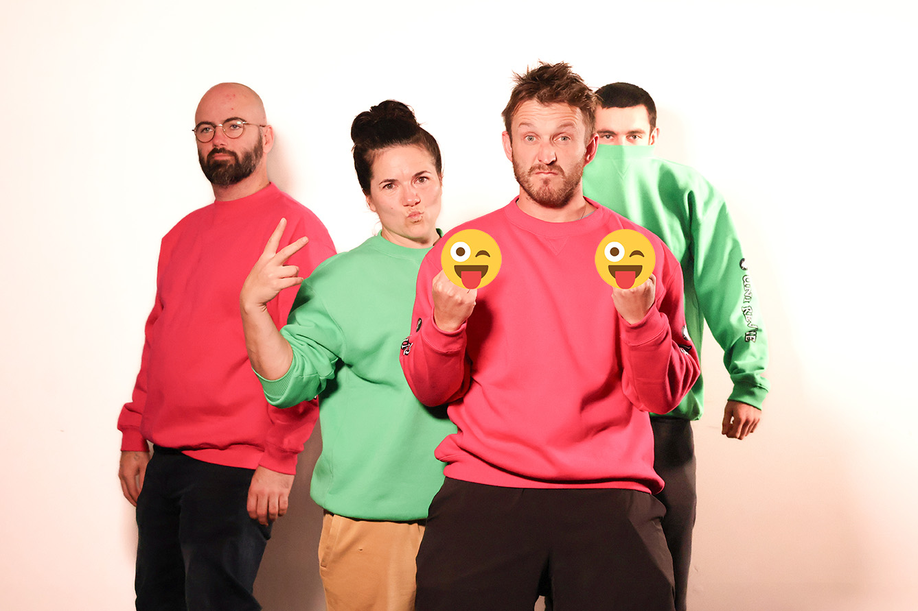 Four people pose in funny/irreverent ways. They each wear a bold colour sweat shirt