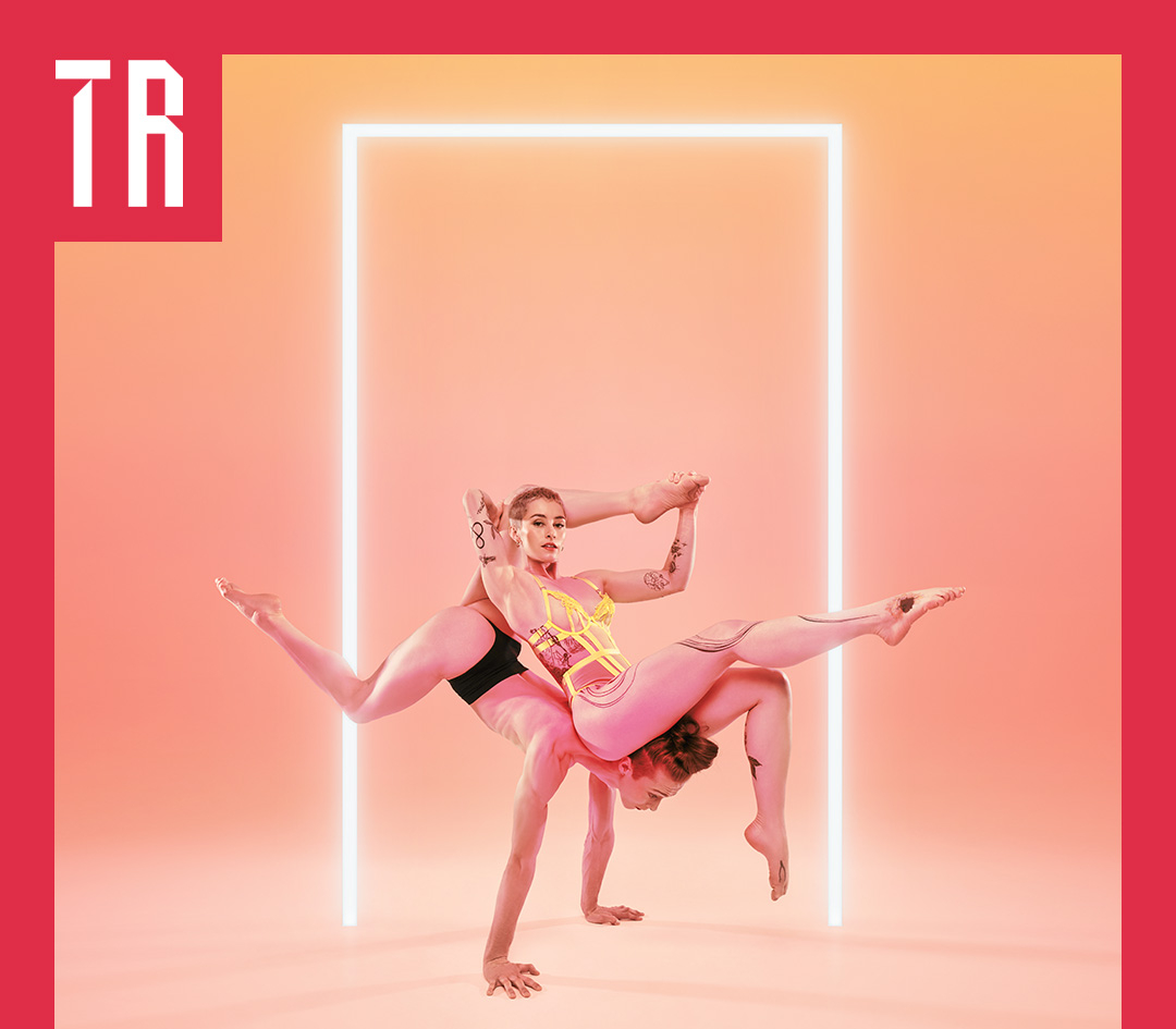 Two female acrobats balance precariously against each other