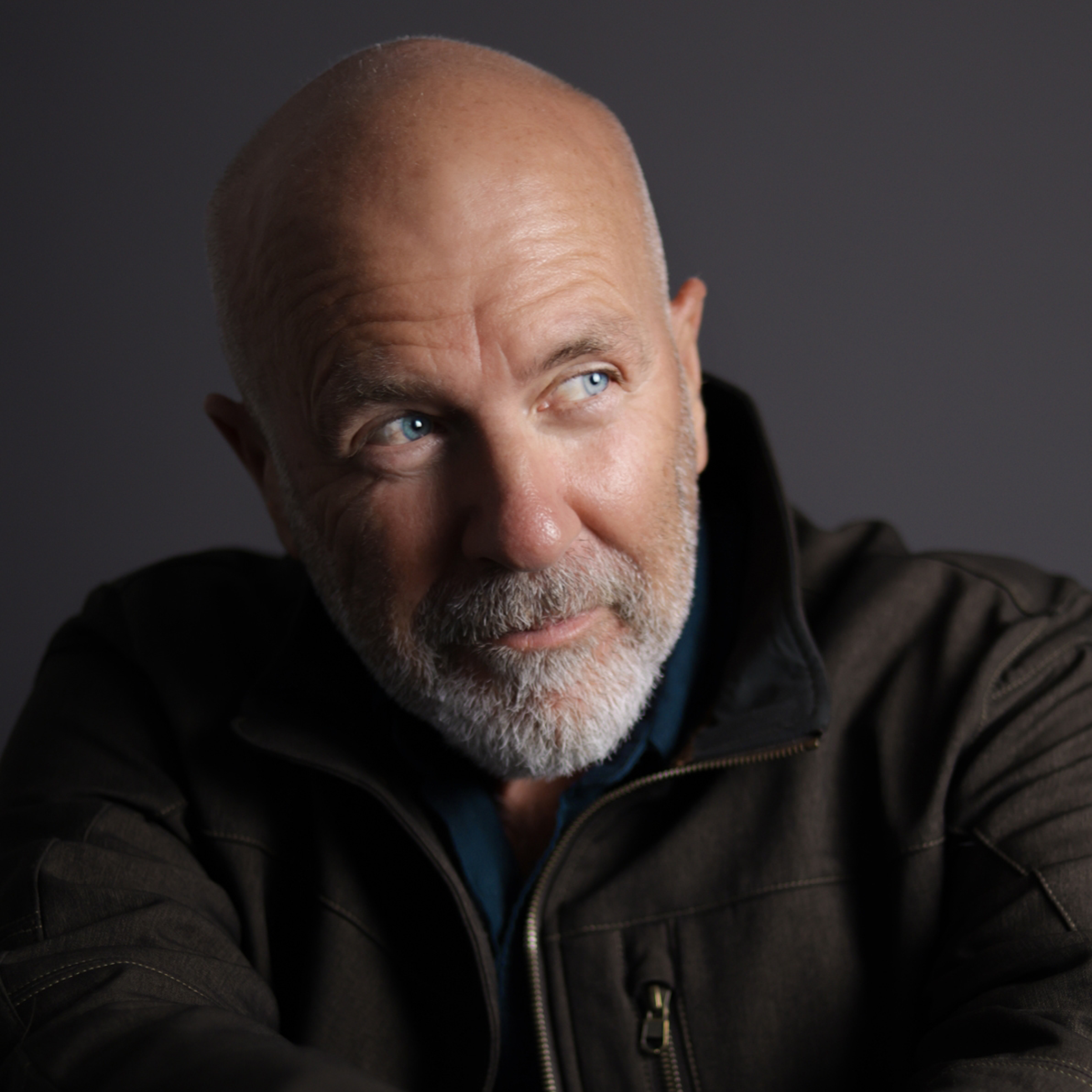 Richard Flanagan A headshot of a man. He is bald and has a grey beard. He is wearing a black jacket and is looking away from the camera.