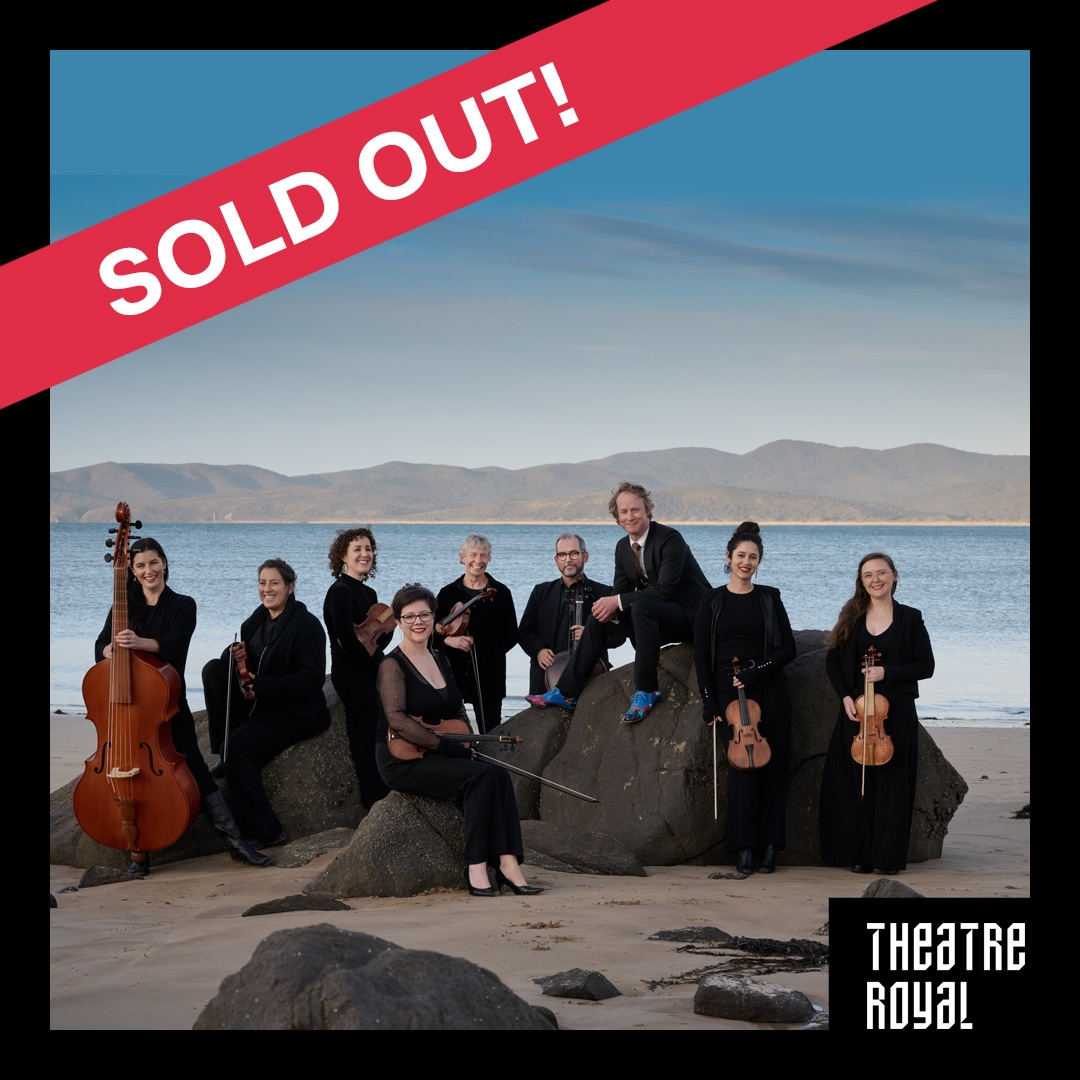 Photo: Albert Comper Van Diemen's Band stand in a group on a Tasmanian beach. They are all wearing black. There is a red banner with white text that says SOLD OUT!