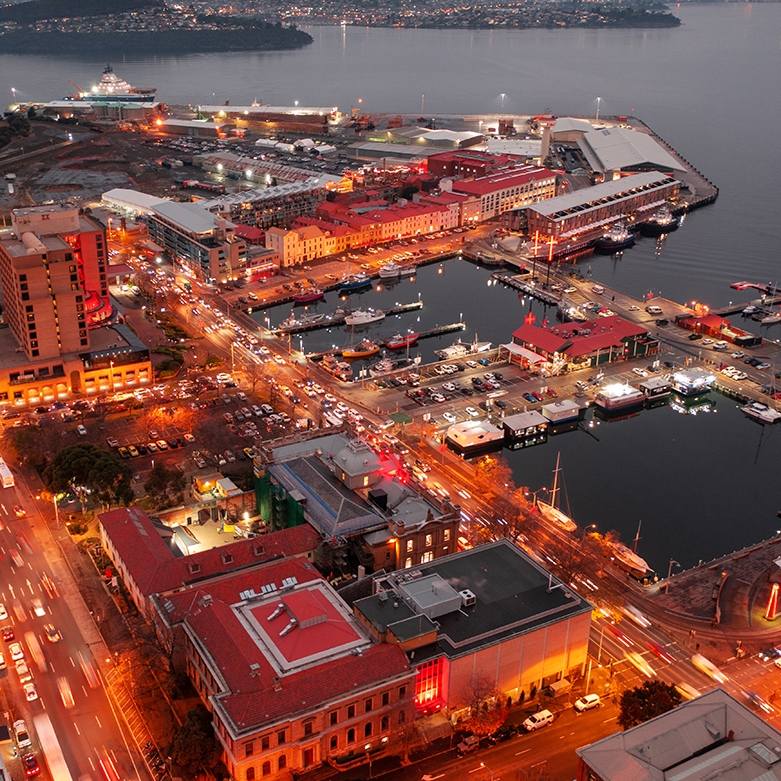 An ariel shot of Hobart waterfront at dusk. There is an orange glow of the lights