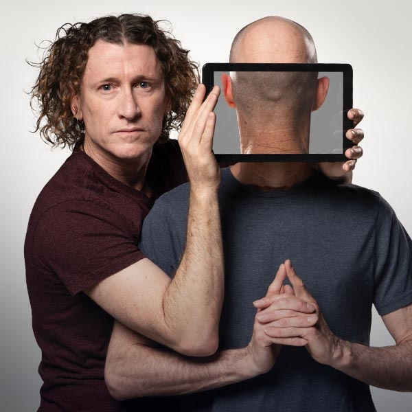 The Umbilical Brothers Two men appear in a strange composition. One had a digital tablet in front of the face of the other, creating an illusion that we are looking at the back of his head.