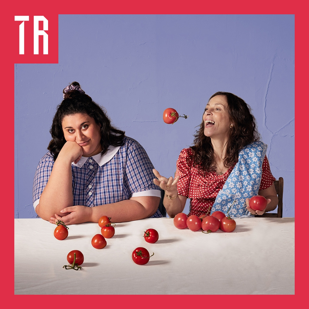 Photo: Daniel Boud A mother and teenage daughter sit at a table. The mother is throwing an apple up in the air. The teenage daughter is wearing a school uniform and looks bored/bemused