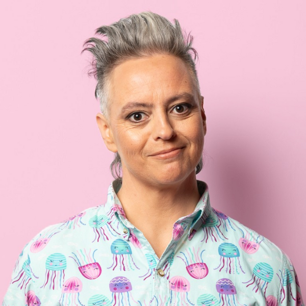 Geraldine Hickey A woaman with a colourful pastel shirt smiles against a pink background