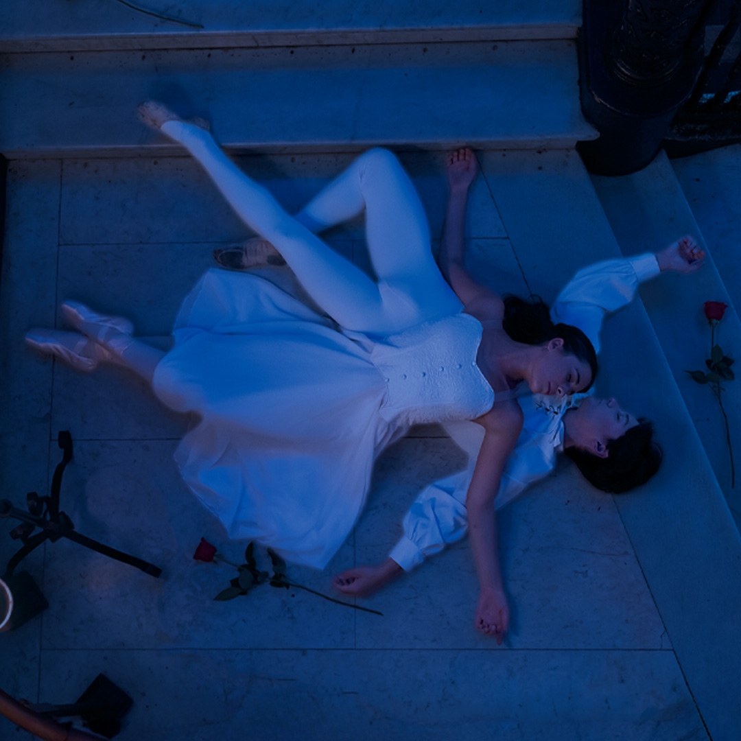 Photo: supplied A blue lit image of a young couple lying across each other as it a sleep surrounded by roses