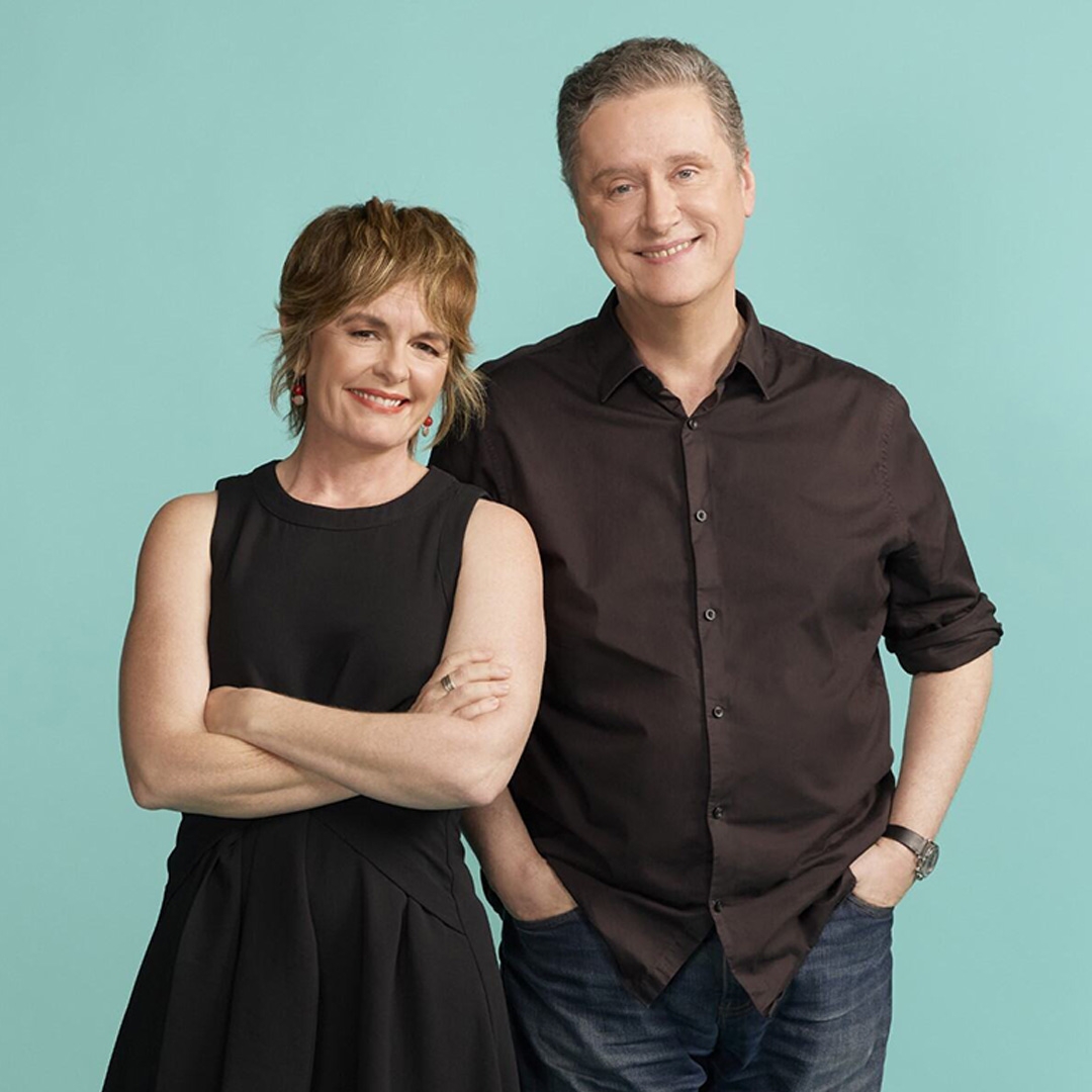 Hero image Sarah Kanowski and Richard Fidler. Image is of Sarah Kanowski and Richard Fidler. They are standing together in front of a turquoise background. Sarah is on the left - she has short light brown hair, is wearing a sleeveless black top, is smiling and has her arms crossed. Richard has short gray hair, is wearing a dark button-up shirt and has one arm behind Sarah.
