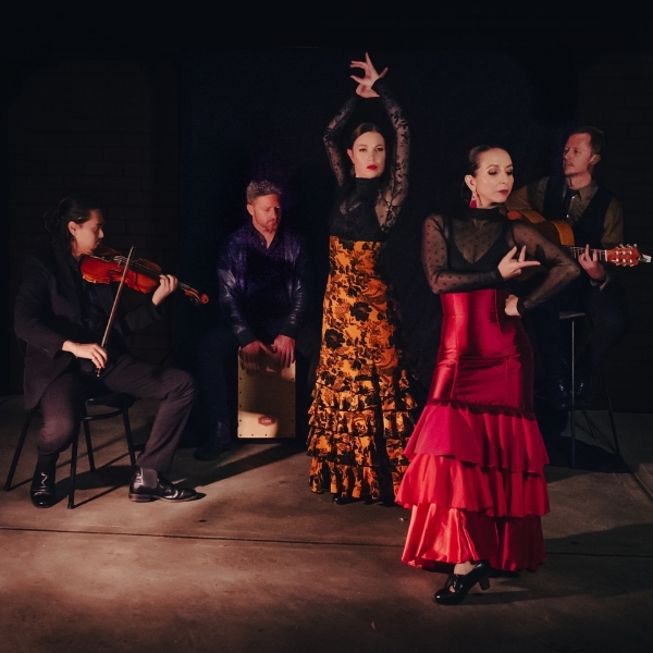 Bandaluzia flamenco hero image A group of 5 performers stand against a black background. There are 3 musicians and 2 dancers