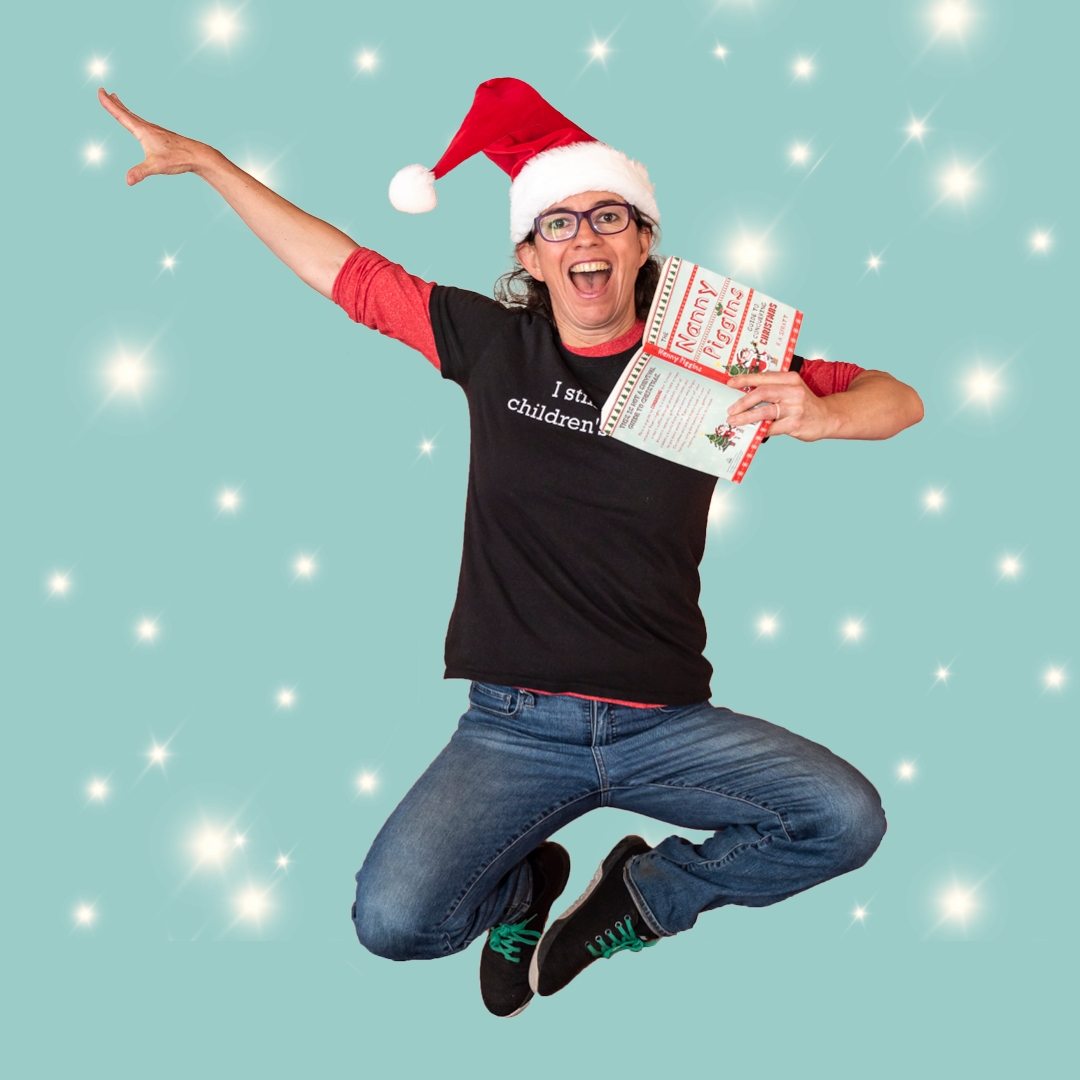 Christmas Stories with R.A. Spratt hero image A person is jumping in the air, in a joyful way, they are holding a book, wearing a santa hat and wearing jeans and a black t-shirt.
