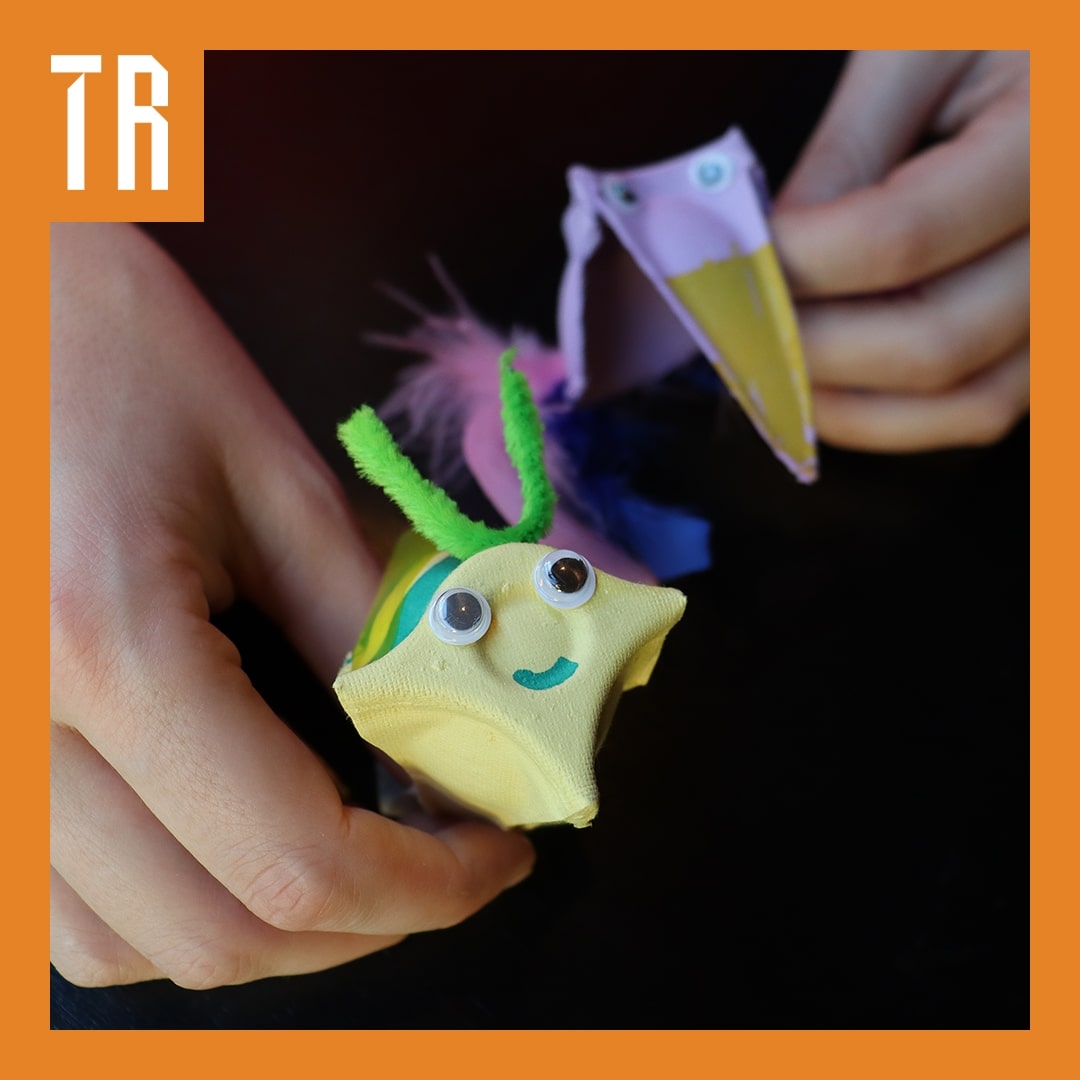 An image of a cardboard bee and bird are being held by a pair of hands