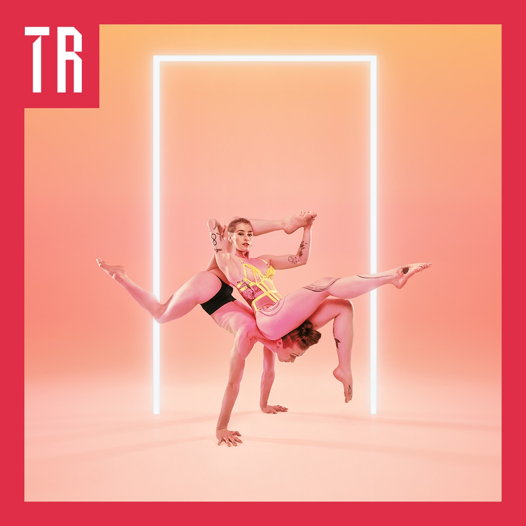 Two female acrobats balance precariously against each other