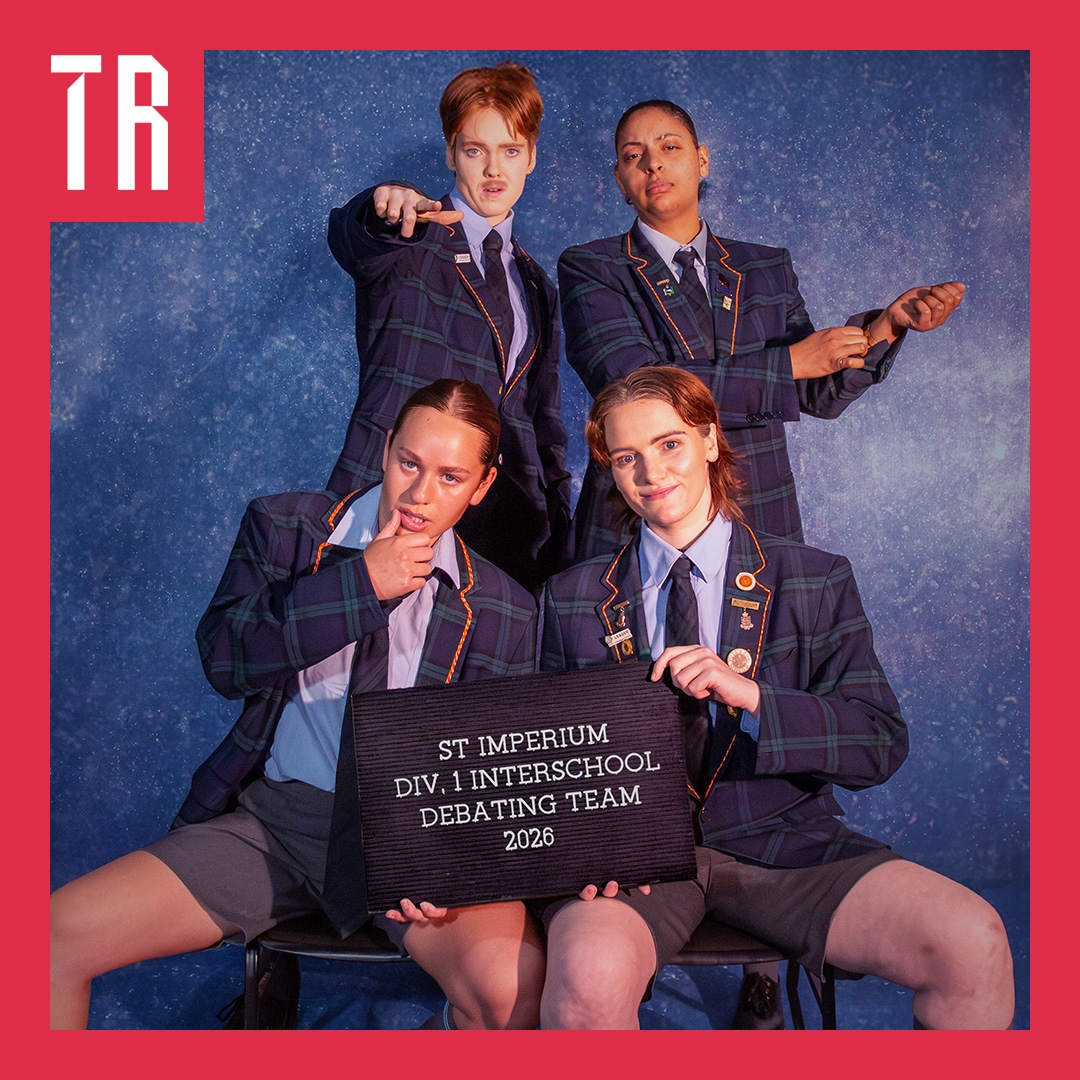 Four non binary and female actors are dressed as elite private school boys, they pose in a cheeky way behind a signs that says St Ignatius debating team