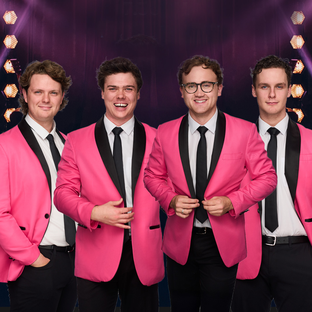 Four young men dressed in pink and black tuxedo jackets, big band style, pose smiling
