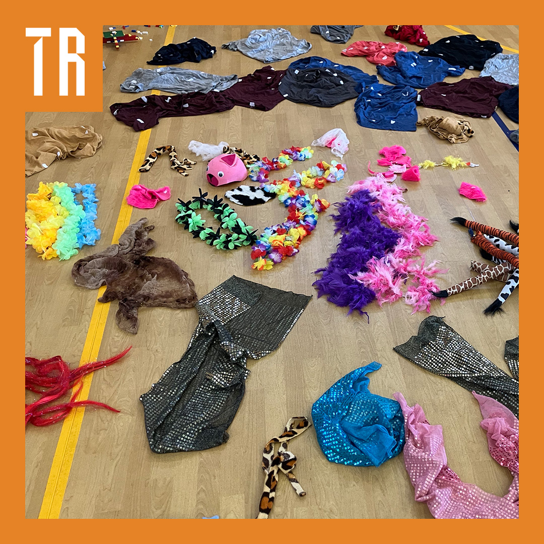 Coloured dress up clothes are sprawled across a floor