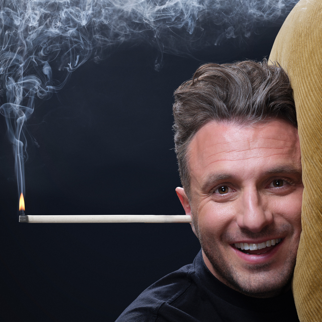 Portrait of comedian Tommy Little. His head is lying on a pillow with an ear candle sticking out of his ear