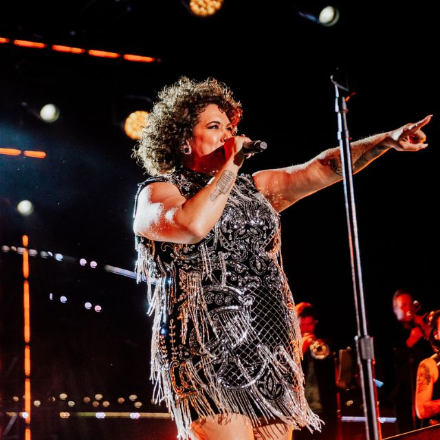 A portrait of singer Casey Donovan, holding amic and looking fierce and joyful