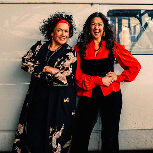 A portrait of singers Vika and Linda, dressed in red and black looking joyful