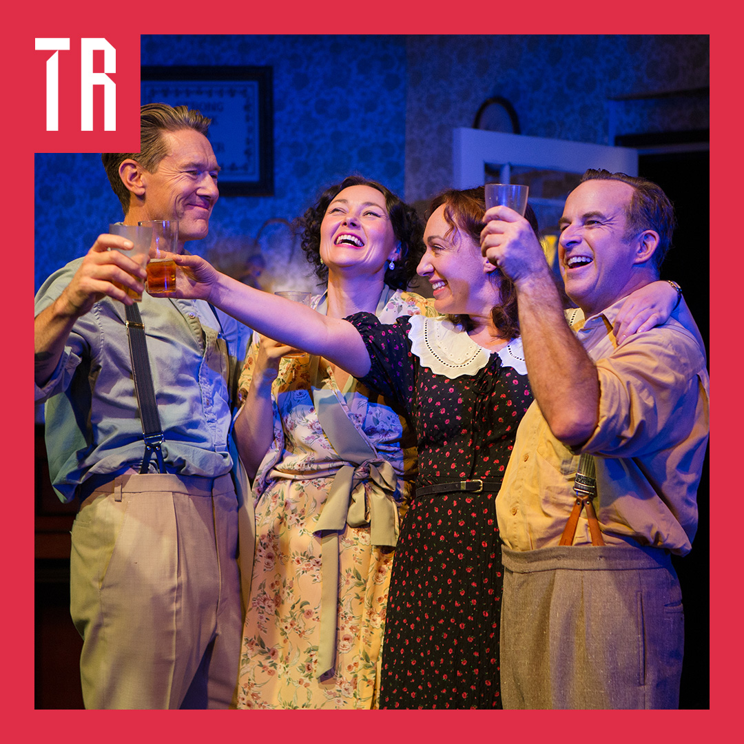 Four audults, two mena nd two women, dressed in 1950's Australiana fashion, smile in a friendly embrace, cheersing drinks