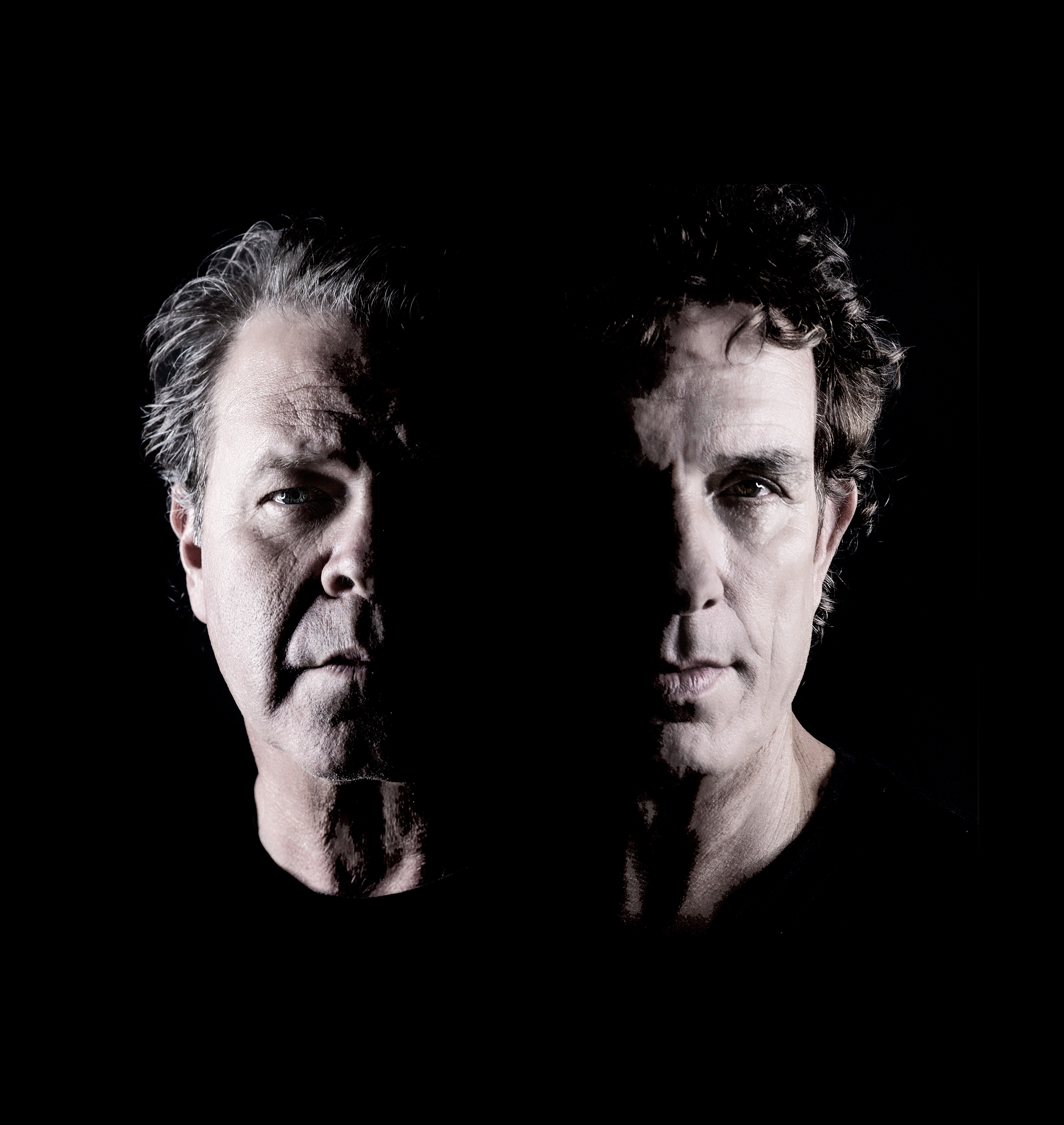 A black and white portrait of  Ian Moss + Troy Cassar-Daley. A close up head shot, like a roman statue, each mans face is half illuminated by light