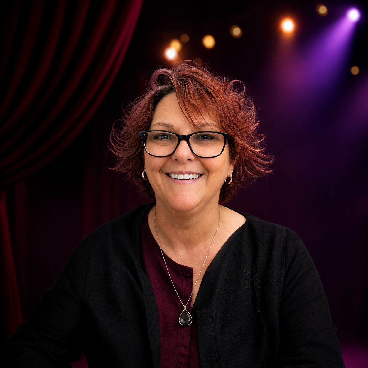 Portrait of Donna Young - a smailing woman with black rimmed glasses and short wavey auburn hair