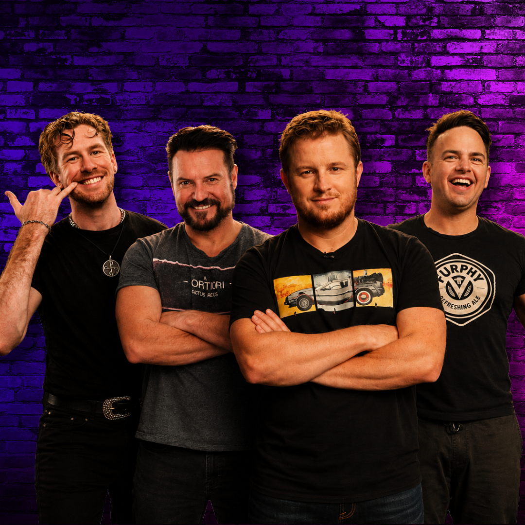 Four male comedians stand in a row, two gave their arms crossed all are smiling. They are wearing dark coloured t-shirts