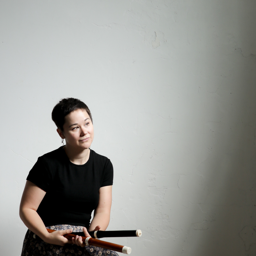 Portrait of musician Meredith Beardmore  - a woman with short pixie hair cut waering a black t-shirt holding a flute, a contemporary and folky look and feel