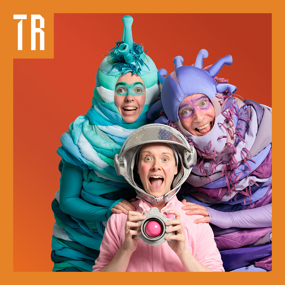 3 actors in bright alien and space costumes