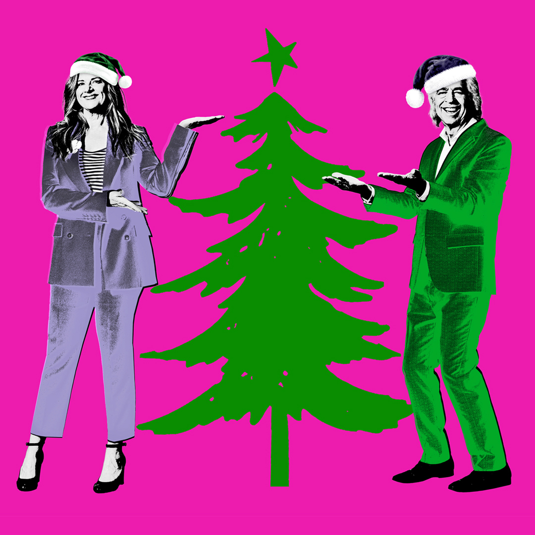 An image of a woman and man standing next to a Christmas tree. They are directing their hands towards it as if presenting it. They are both wearing suits and Santa hats.
