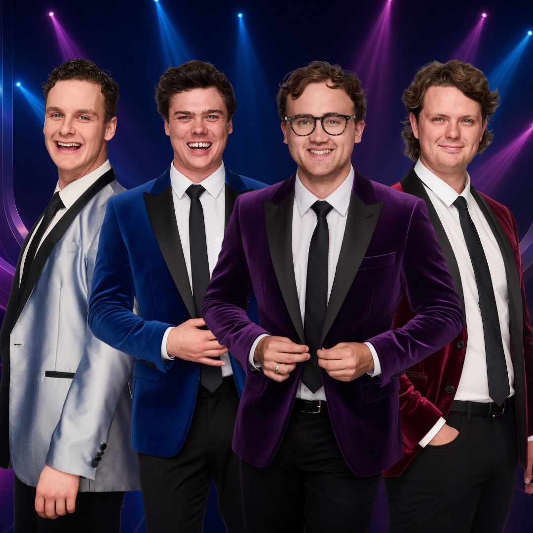 Four smiling men stand together in formal black-tie outfits, wearing satin and velvet blazers in silver, blue, purple, and burgundy. They pose against a dark stage backdrop illuminated by vibrant blue and magenta spotlights.