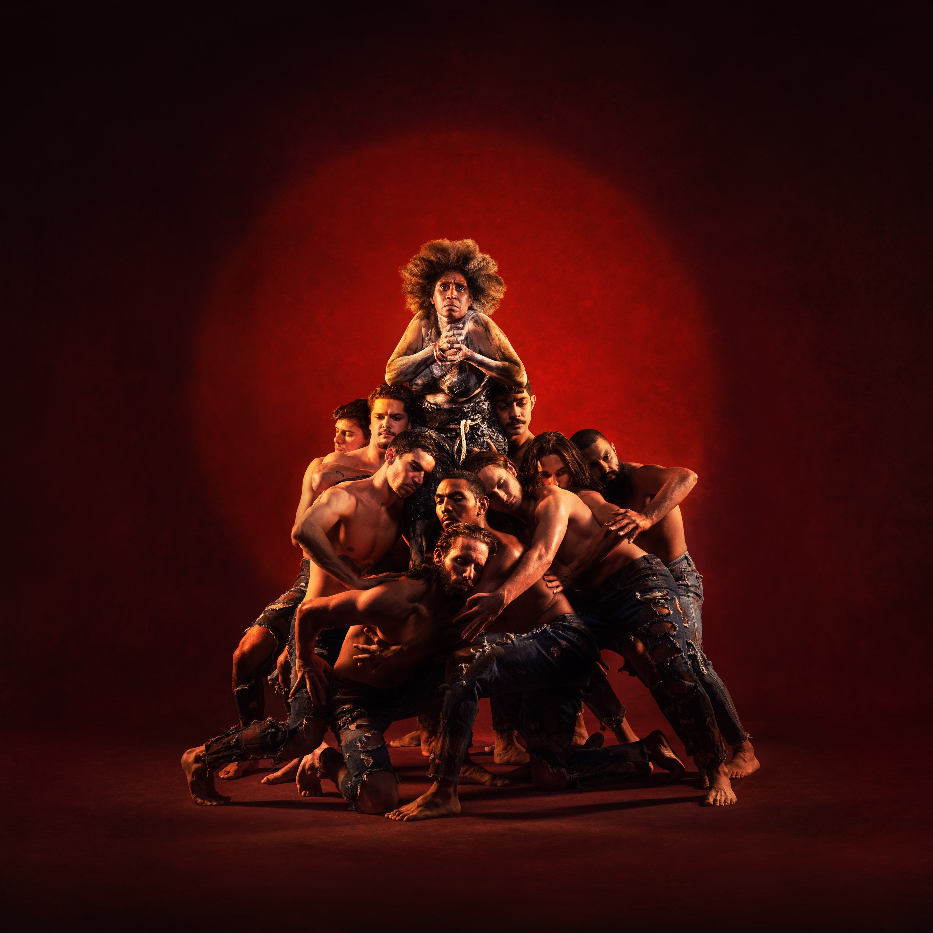 Wadjung: Not the Past Wadjung: Not the Past. Image with Red Background. Group of men hold up and embrace the Mother.