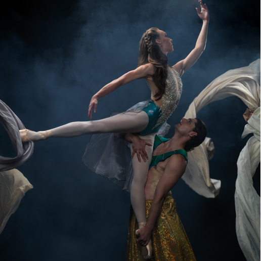 Male Ballet Dancer holding female dancer above head in arabesque