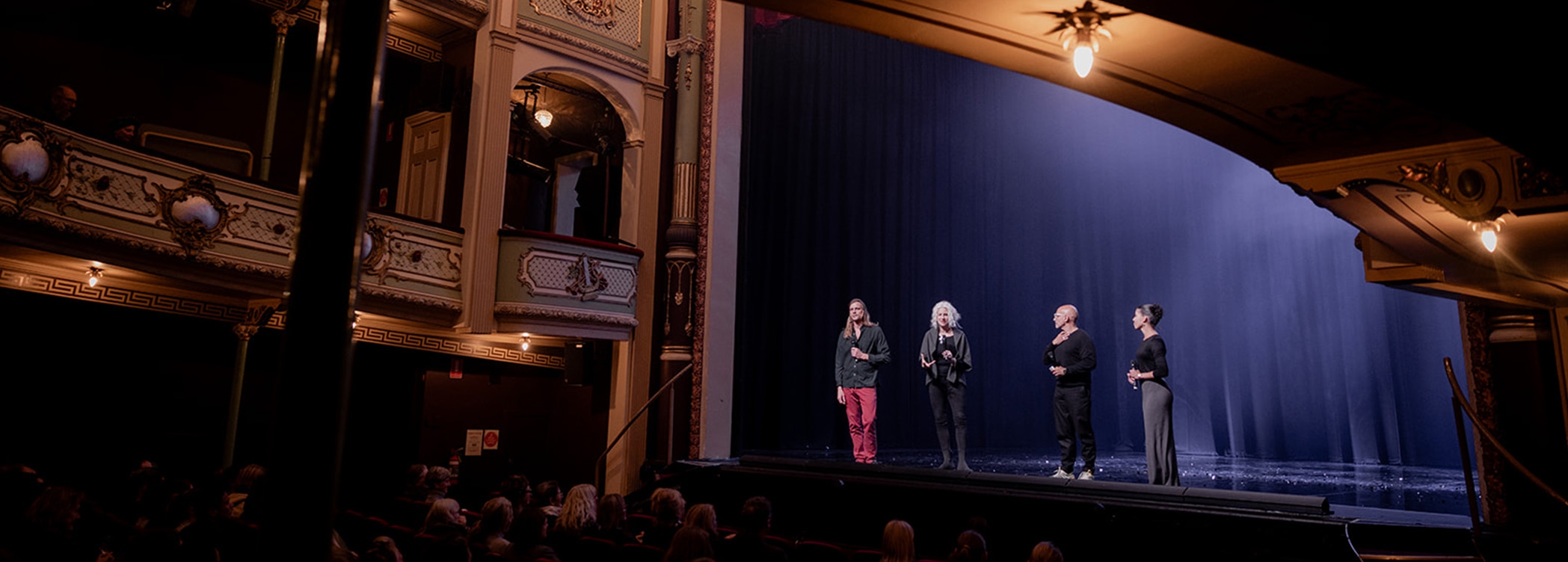 Four people stand on the Theatre Royal stage