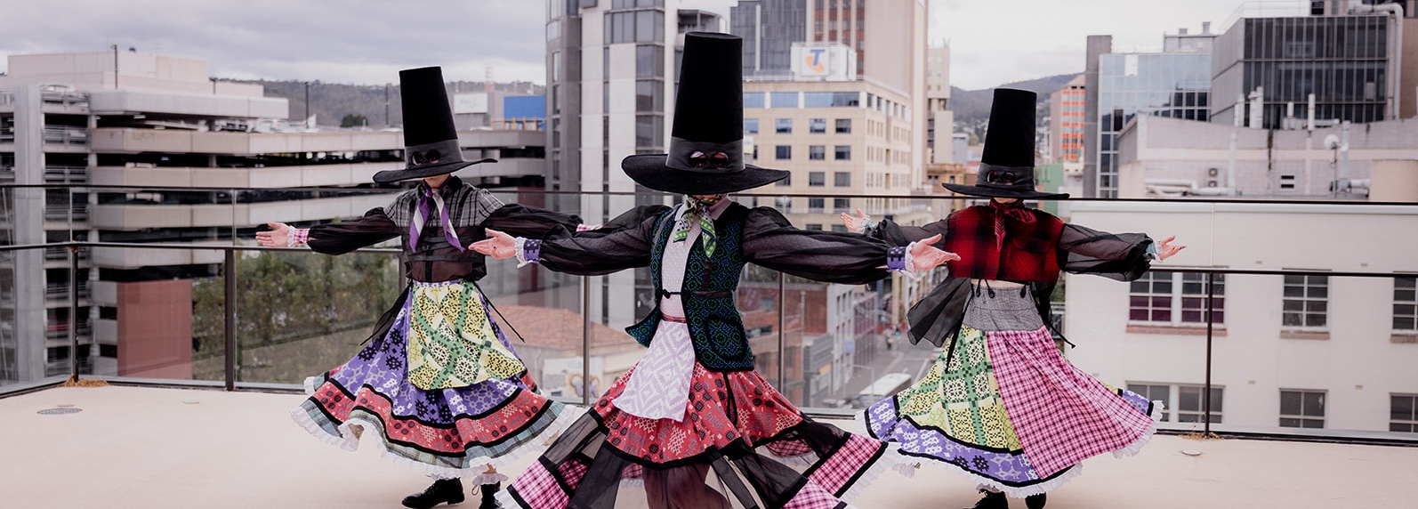 The dancers twirl in very colourful patchwork skirts and oversized, tall black hats which cover their faces.